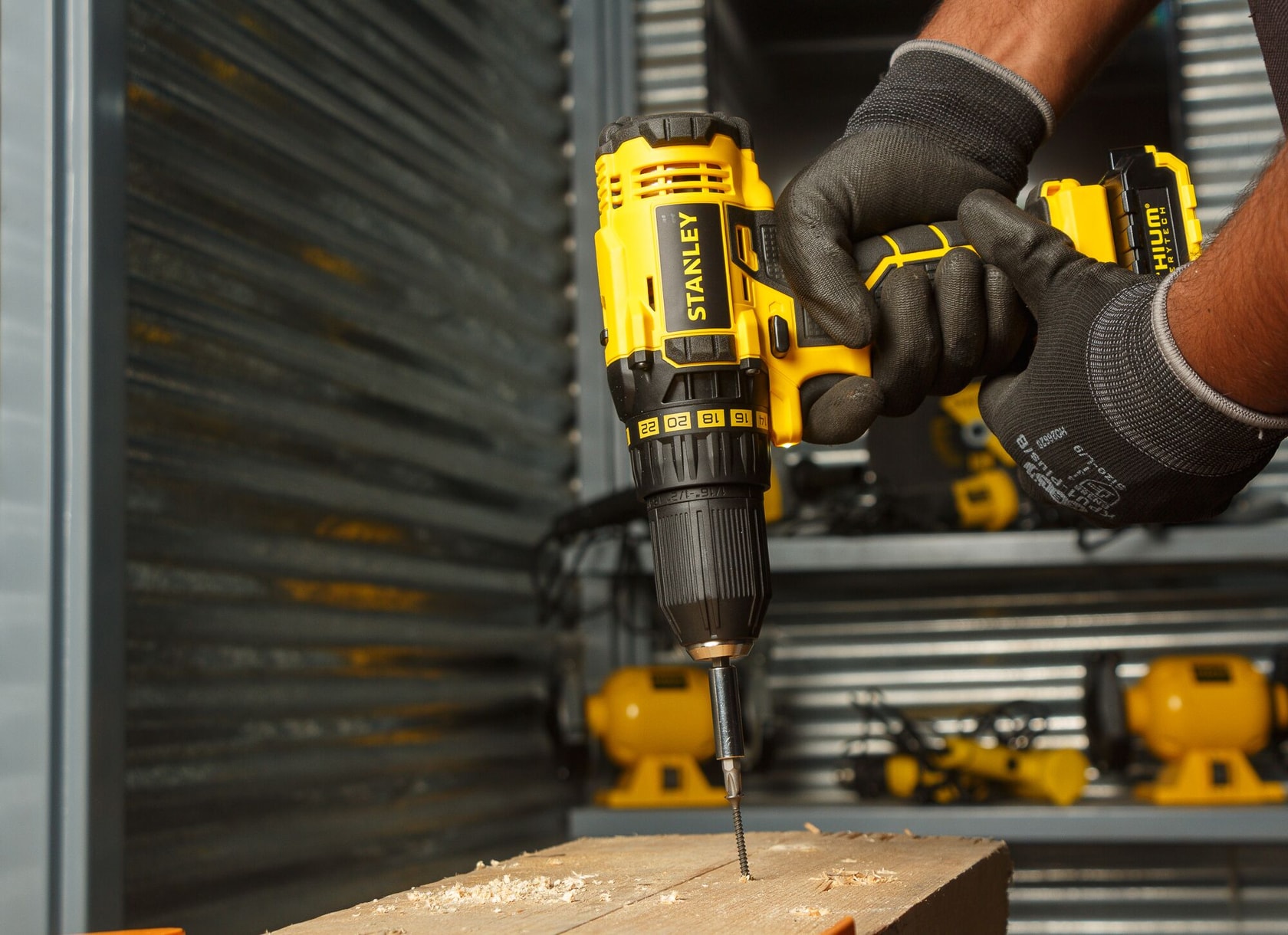 Stanley SCD20C2K taladro inalámbrico en uso perforando madera, primer plano, herramienta amarilla y negra.